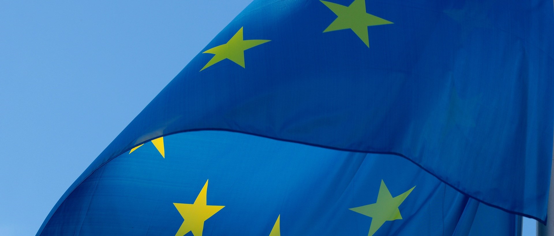 Den blåa Europeiska flaggan vajar i vinden, solen lyser på dom gula stjärnorna.